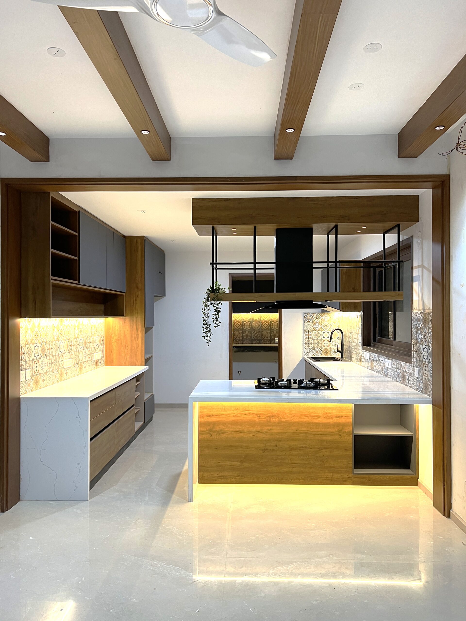 Modular kitchen with island, patterned tile backsplash, timber ceiling beams and integrated lighting